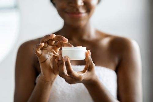 Young African American adult woman getting ready to apply body lotion during the Winter